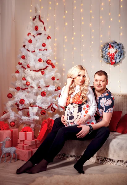 Famiglia felice nel soggiorno, dietro l'albero di Natale decorato, la luce dà un'atmosfera accogliente. Tema di Capodanno e Natale — Foto Stock