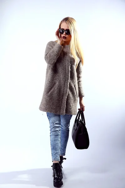 Sexy Beauty Girl. Fashion Blonde. Portrait of a girl dressed in grey coat, wearing a black bag, posing on a studio background. — Stock Fotó