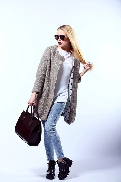 Sexy Beauty Girl. Fashion Blonde. Portrait of a girl dressed in grey coat, wearing a black bag, posing on a studio background. — 图库照片