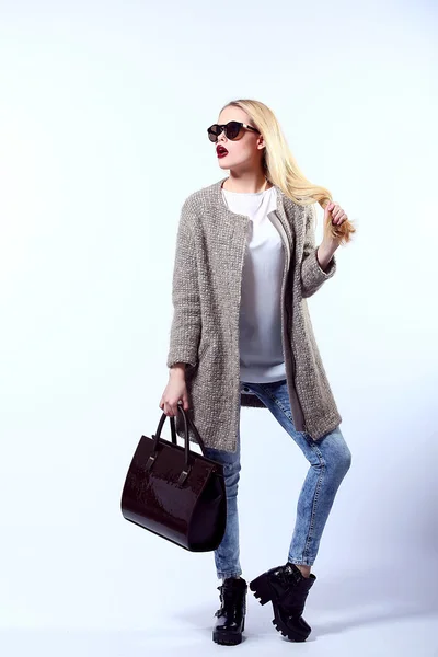 Sexy Beauty Girl. Fashion Blonde. Portrait of a girl dressed in grey coat, wearing a black bag, posing on a studio background. — Stock Fotó