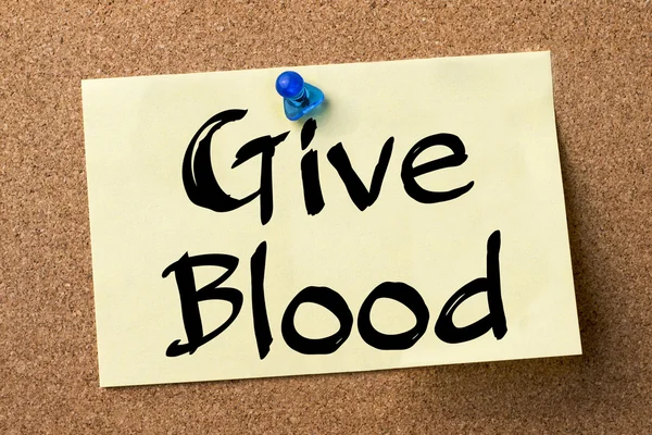 Give Blood - клейкая этикетка, закрепленная на доске объявлений — стоковое фото