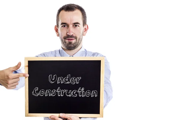 Under Construction - Young businessman with blackboard — Stock Photo, Image