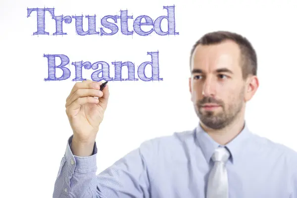 Trusted Brand - mladý podnikatel psaní modrý text — Stock fotografie