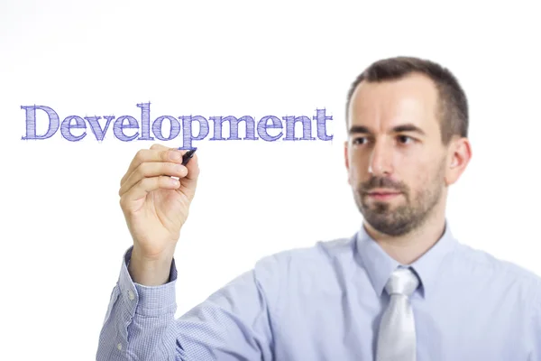 Desenvolvimento - Jovem empresário escrevendo texto azul na superfície transparente — Fotografia de Stock