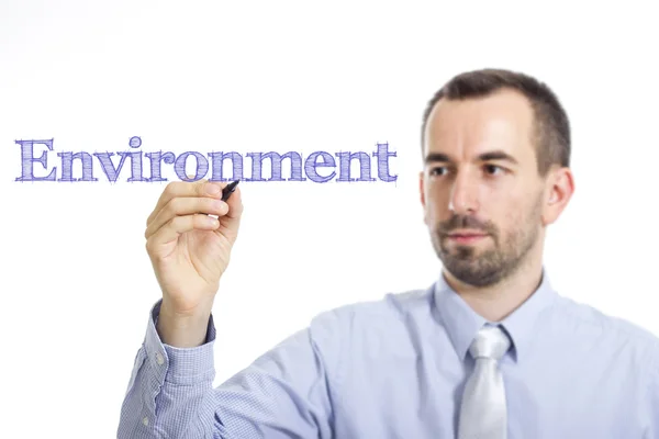 Environment - Young businessman writing blue text on transparent surface — Stock fotografie