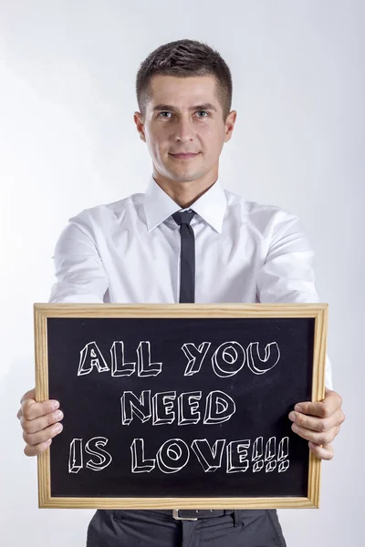 Todo lo que necesitas es amor!!! - Joven empresario sosteniendo pizarra con texto —  Fotos de Stock