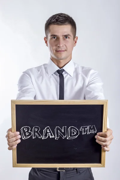 BRAND tm - Young businessman holding chalkboard with text — Stock Photo, Image