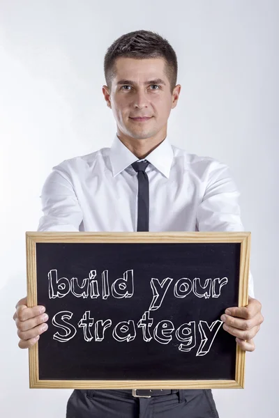 Build your strategy - Young businessman holding chalkboard with text — Stock Photo, Image