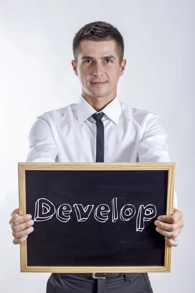 Develop - Young businessman holding chalkboard with text — Stock Photo, Image