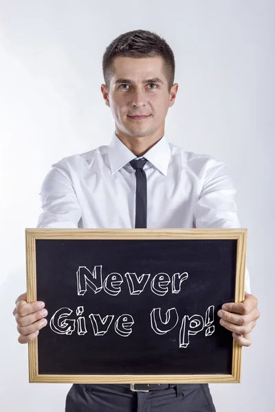 Never Give Up! - Young businessman holding chalkboard — Stock Photo, Image