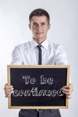 To be continued - Young businessman holding chalkboard clipart