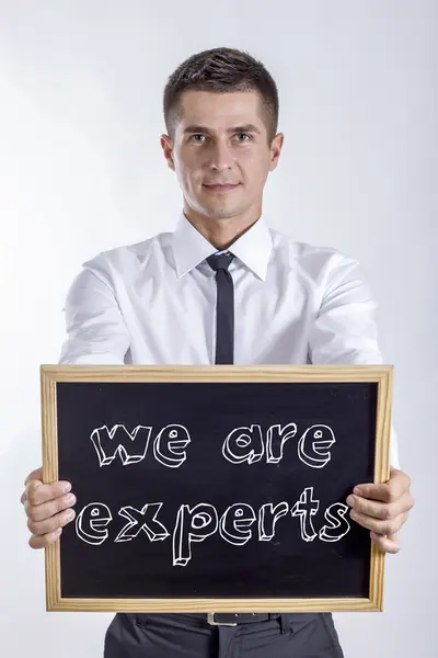 Somos expertos - Joven empresario sosteniendo pizarra — Foto de Stock