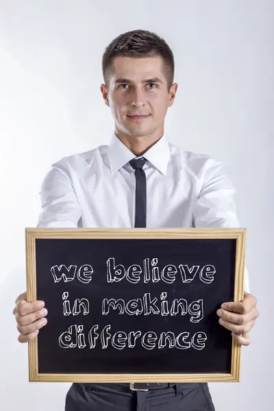 Wierzymy w podejmowania różnica - młody biznesmen posiadania tablicy — Zdjęcie stockowe
