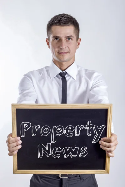 Notícias da propriedade - Jovem empresário segurando quadro — Fotografia de Stock