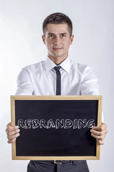 REBRANDING - Young businessman holding chalkboard with text — Stock Photo, Image