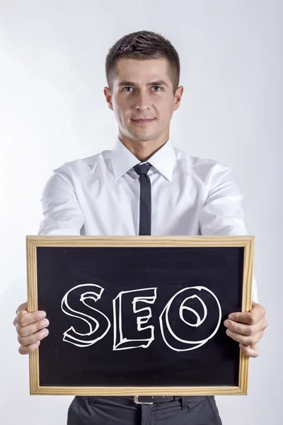 SEO - молодий бізнесмен тримає крейдяну дошку — стокове фото