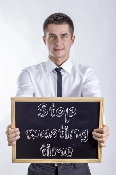 Sluta slösa tid - ung affärsman holding svarta tavlan — Stockfoto