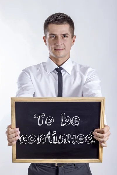 To be continued - Young businessman holding chalkboard — Stock Photo, Image