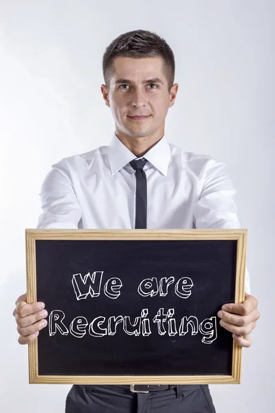 Nous recrutons - Un jeune homme d'affaires tenant un tableau noir — Photo