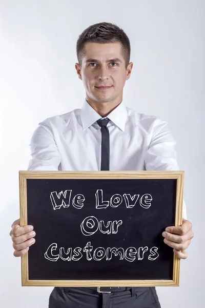 Αγαπάμε τους πελάτες μας - ο νεαρός επιχειρηματίας κρατώντας Μαυροπίνακας — Φωτογραφία Αρχείου