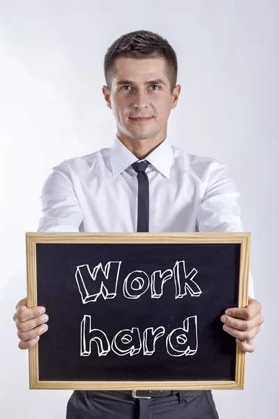 Trabalho duro - Jovem empresário segurando quadro — Fotografia de Stock