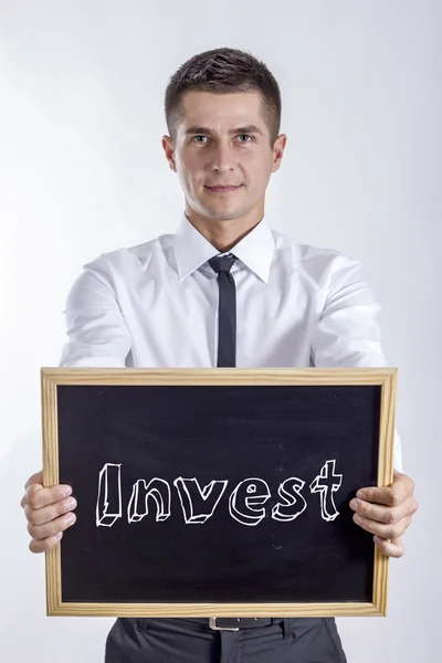 Invest - Jovem empresário segurando quadro com texto — Fotografia de Stock
