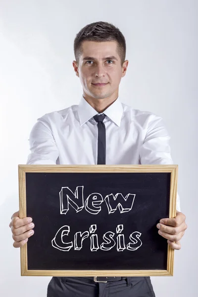Ny kris - ung affärsman holding svarta tavlan med text — Stockfoto