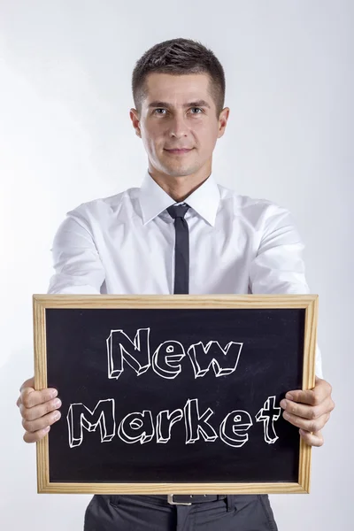 New Market - Young businessman holding chalkboard with text — Stock Photo, Image