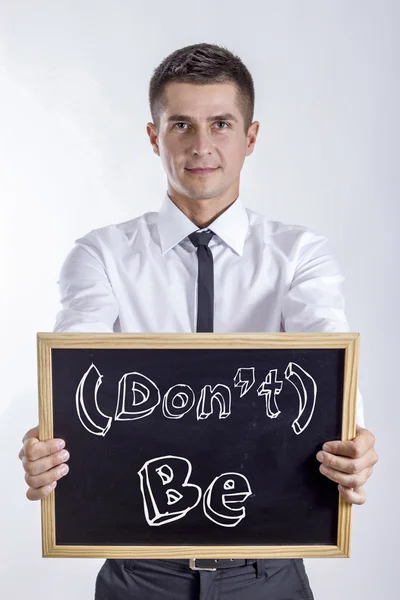 (Don't) Be - Giovane uomo d'affari che tiene la lavagna con testo — Foto Stock