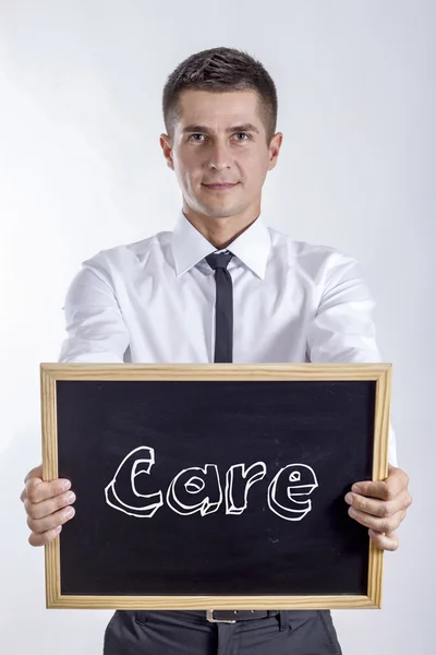 Péče - mladý podnikatel drží tabule s textem — Stock fotografie