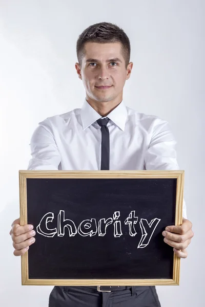Caridade - Jovem empresário segurando quadro com texto — Fotografia de Stock