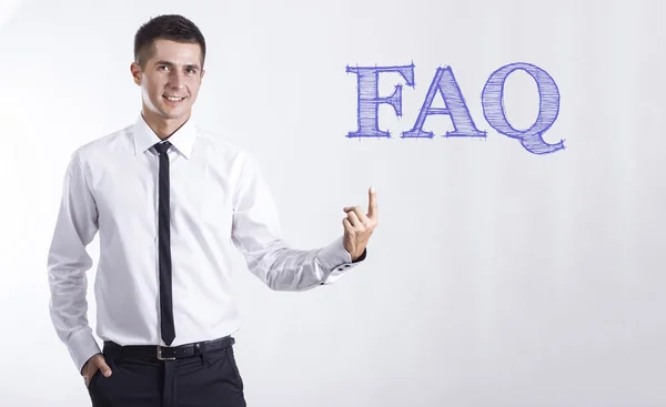 FAQ - Jeune homme d'affaires souriant pointant du doigt le texte — Photo