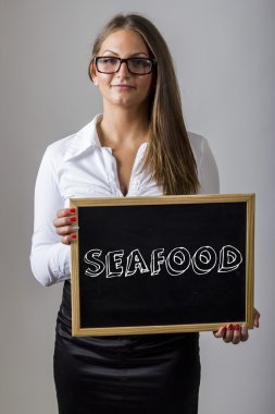 SEAFOOD - Young businesswoman holding chalkboard with text