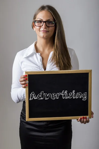 Advertising - Young businesswoman holding chalkboard with text — Stockfoto