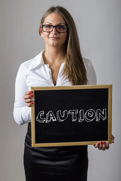 CAUTION - Young businesswoman holding chalkboard with text — Stock Fotó