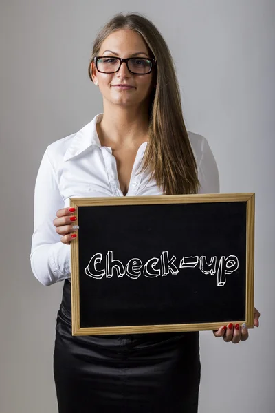 Check-up - Young businesswoman holding chalkboard with text — Stock fotografie