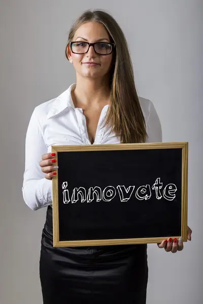 Innovate - Young businesswoman holding chalkboard with text — ストック写真