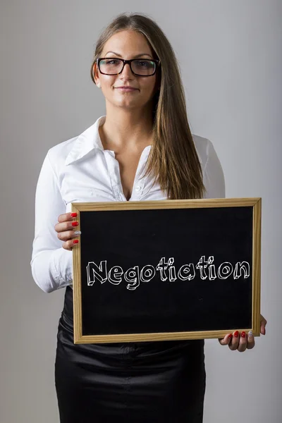 Negotiation - Young businesswoman holding chalkboard with text — Stockfoto