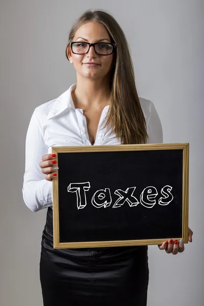 Taxes - Young businesswoman holding chalkboard with text — Stockfoto