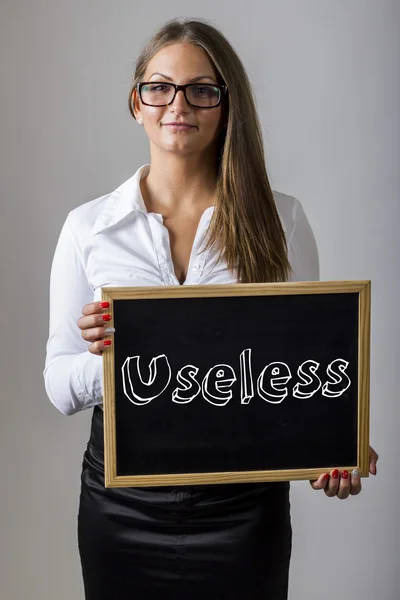 Useless - Young businesswoman holding chalkboard with text — Stock Fotó