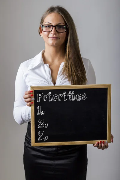 Priorities 1. 2. 3. - Young businesswoman holding chalkboard wit — Stock fotografie