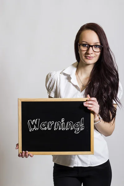 Warning! - Young businesswoman holding chalkboard — Stock Photo, Image