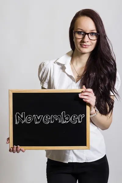 Noiembrie - O tânără femeie de afaceri care deține tablă de cretă — Fotografie, imagine de stoc
