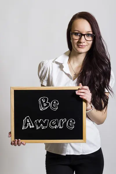 Be Aware - Young businesswoman holding chalkboard — Stock Photo, Image