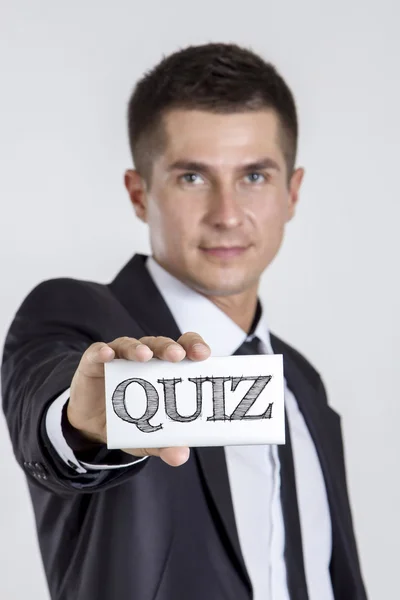 Quiz - junger Geschäftsmann hält eine weiße Karte mit Text — Stockfoto