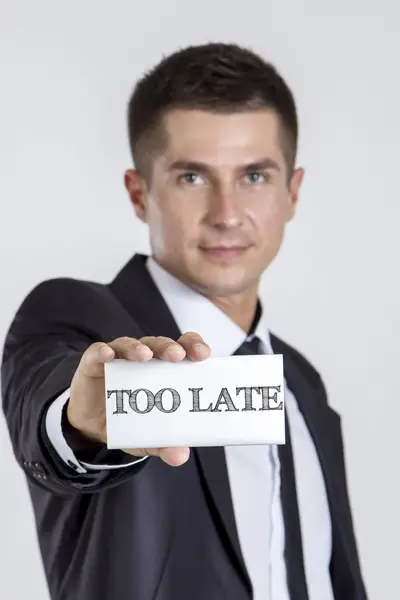 TOO LATE - Young businessman holding a white card with text — Stock Photo, Image