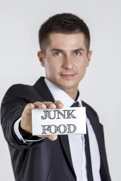 JUNK FOOD - Young businessman holding a white card with text — Zdjęcie stockowe