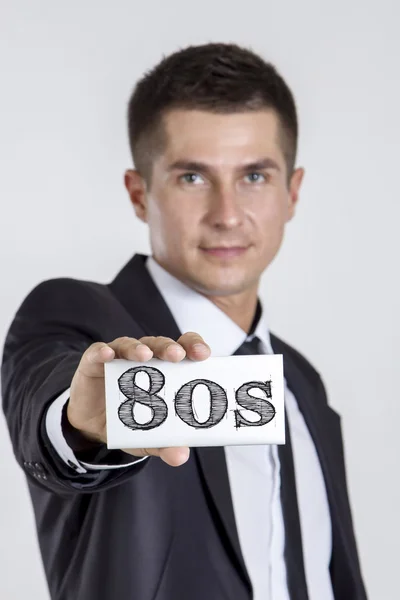 80-ті - молодий бізнесмен тримає білу картку з текстом — стокове фото