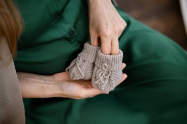 Beyaz kazaklı kadın elleri ve tahta arka planda örülmüş çoraplar. Kapat - kapat.