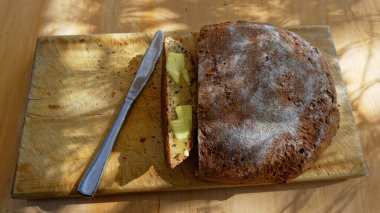 Ekmek tahtasında ev yapımı ekmek duruyor, bir dilim tereyağlı ve yemeye hazır.